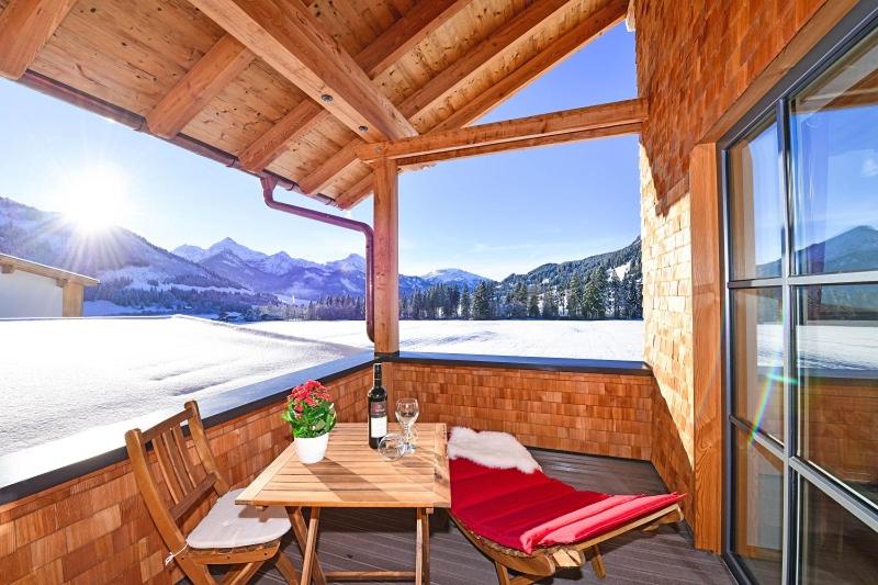 einen Holztisch und Stühle auf einem Balkon mit Aussicht in der Unterkunft Sonn Alpin - Ferienwohnungen in Grän