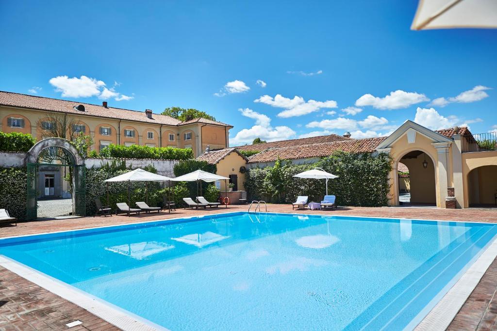 una gran piscina con sillas y sombrillas en Sina Villa Matilde, en Romano Canavese