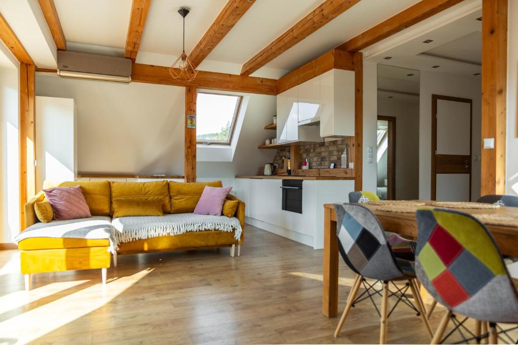 Una sala de estar con un sofá amarillo y una cocina. en SURF STYLE APARTAMENT, en Muszyna