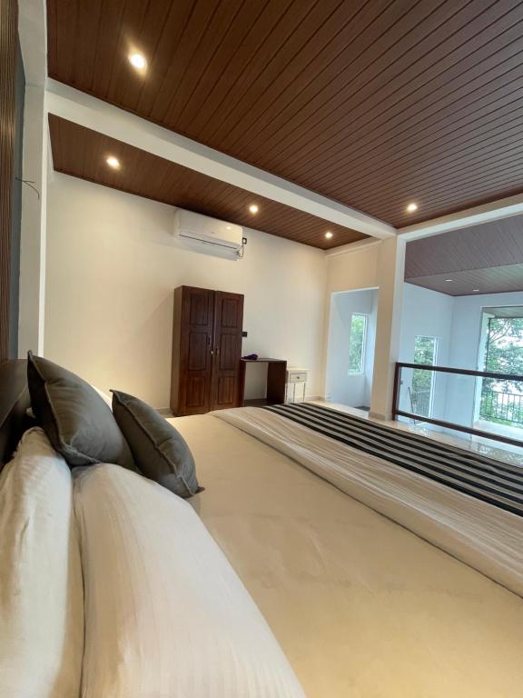 a large bed with pillows in a large room at Ella waterfall view in Ella