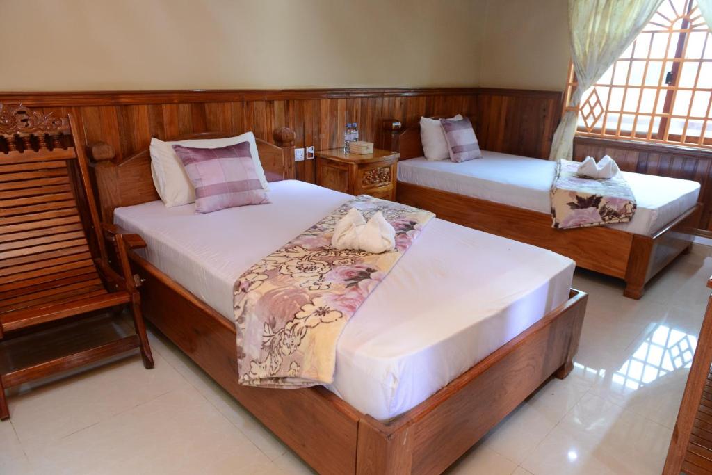 two beds in a room with wooden walls at Javier Guesthouse in Tbeng Meanchey