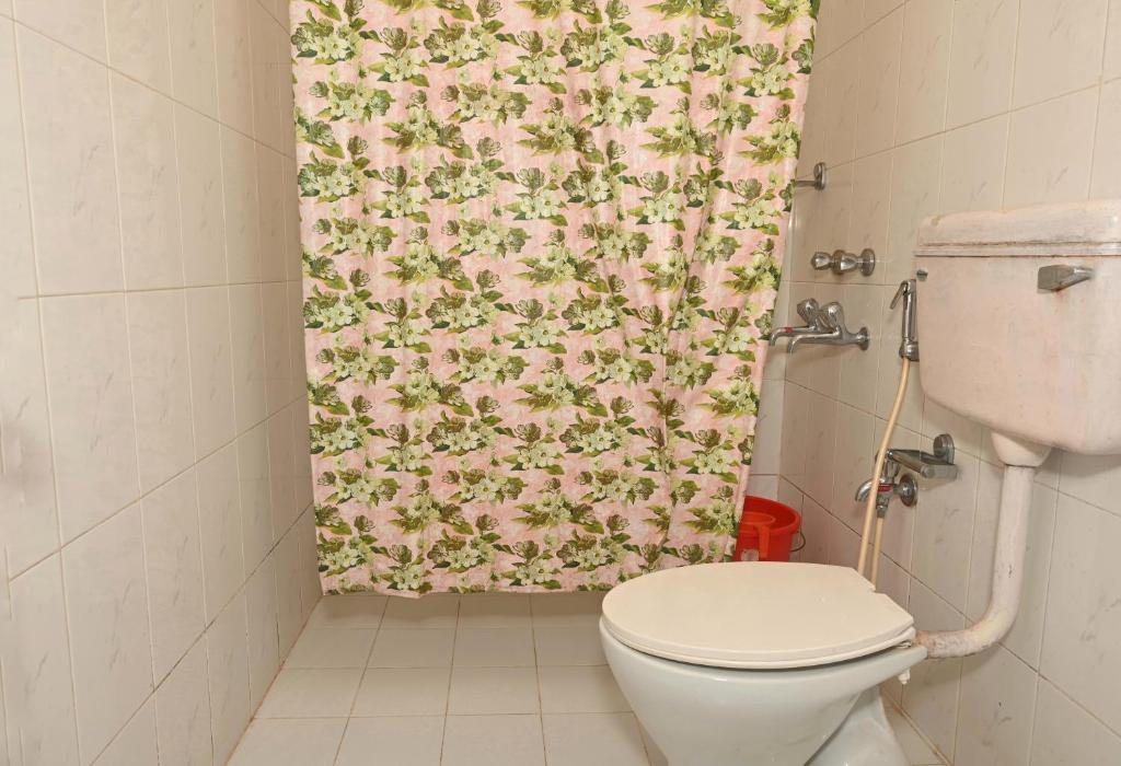 Un baño con inodoro y cortina de ducha. en Libton Manor, en Candolim