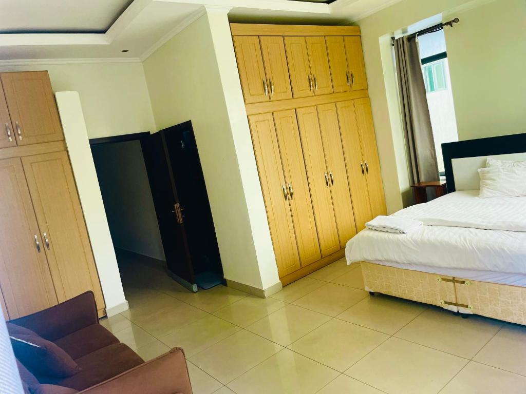 a bedroom with a bed and wooden cabinets and a chair at KiGALI HORIZON HOMES in Kigali