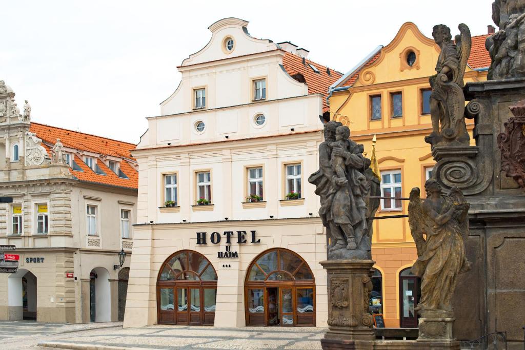Hotel U Hada Žatec في زاتيك: مبنى الفندق امامه تمثال