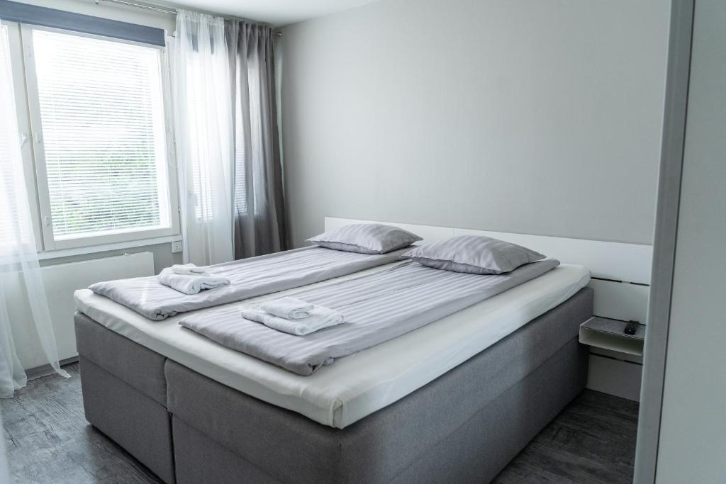 een groot bed in een witte kamer met een raam bij Apartment Siihtala - suuri saunallinen huoneisto in Joensuu