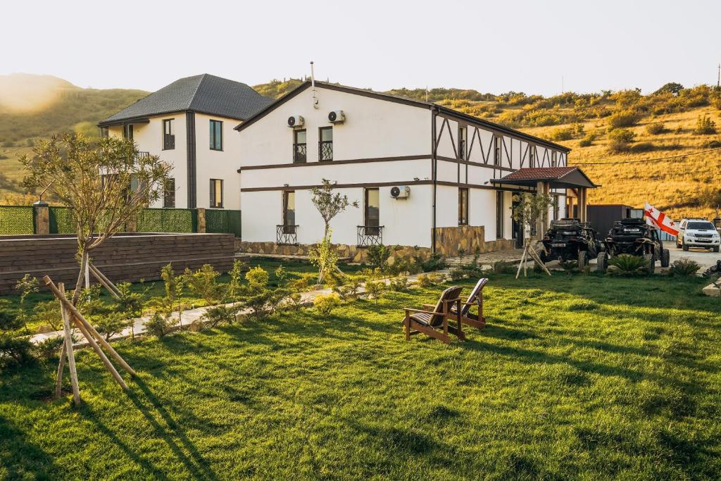 a white house on a hill with a grass yard at Camp Hotel Pura Vida in Tbilisi City