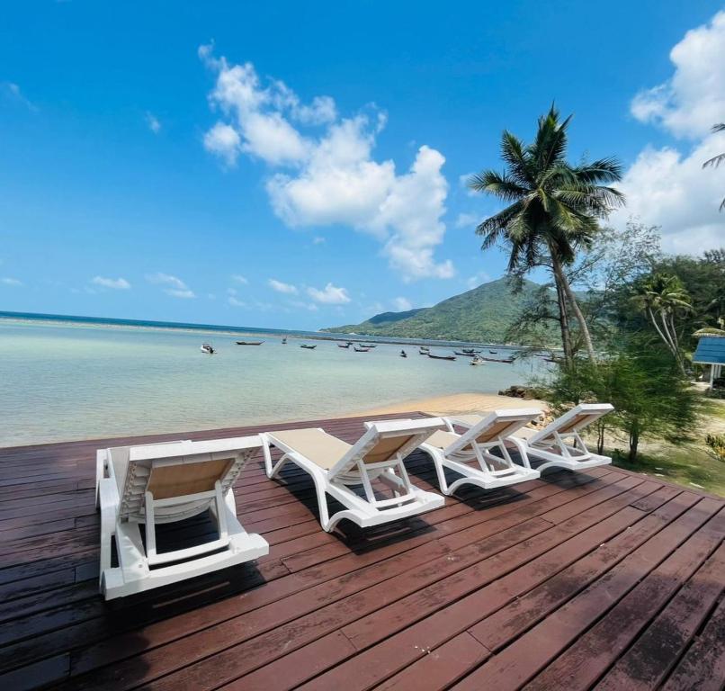 Una terraza de madera con tumbonas en la playa. en Seaside Cove, en Ban Madua Wan