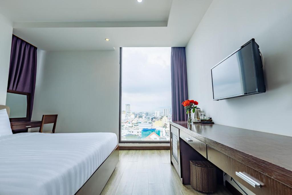 a hotel room with a bed and a flat screen tv at GOLDEN SUN DANANG Hotel in Da Nang