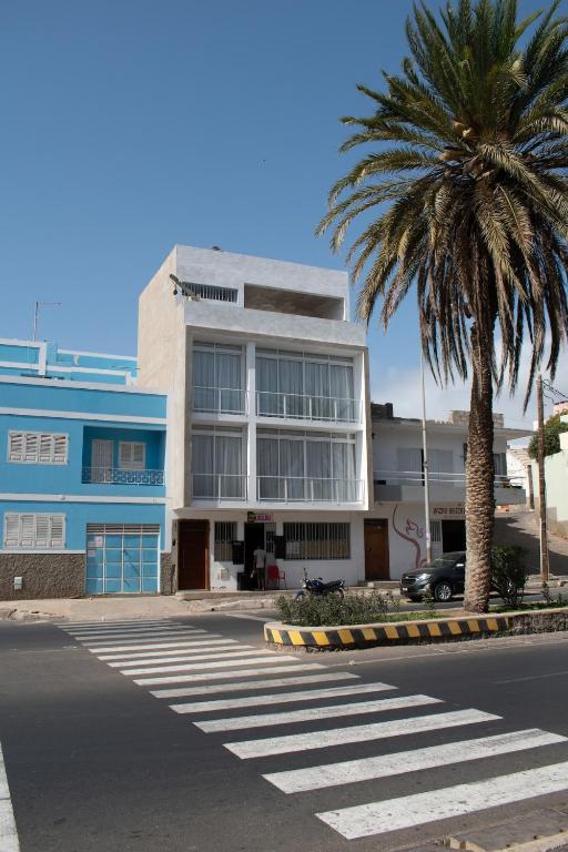 a building with a palm tree in front of a street at Casa Miranda in Mindelo