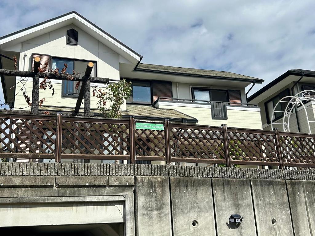 a man standing on a fence in front of a house at Guest House YADOKARI in Hirakata