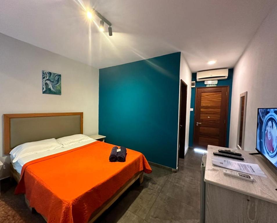 a bedroom with a bed with an orange blanket and a tv at Royal Attitude in Port Mathurin