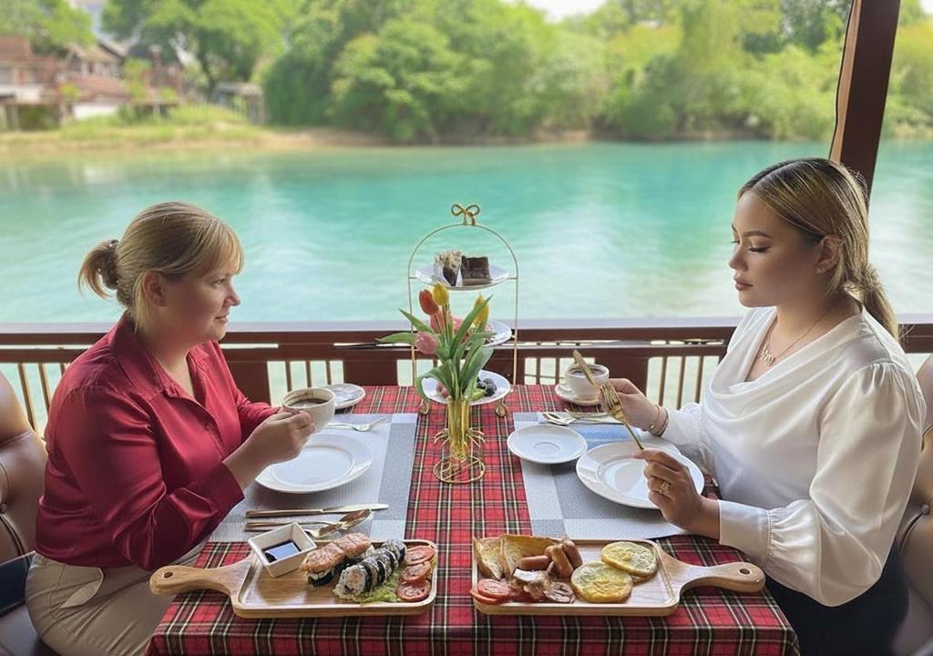 deux femmes assises à une table en train de manger dans l'établissement Intimate Riverside Resort Vang Vieng, à Vang Vieng