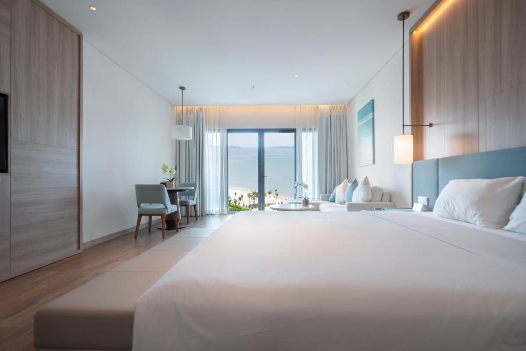 a bedroom with a large white bed and a table at Căn hộ cao cấp tại ALaCarte Ha Long Bay Hotel Residence in Ha Long
