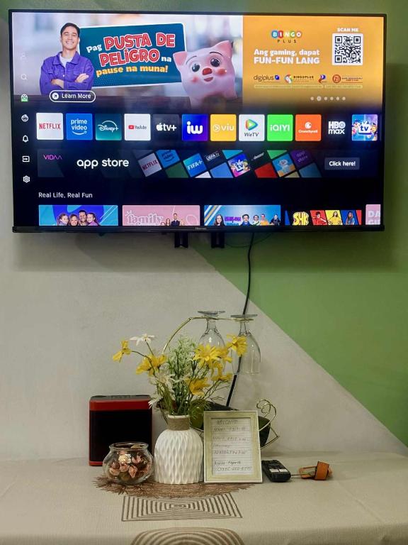 a television on a wall with a vase of flowers on a table at Shell Residence Pasay City in Manila