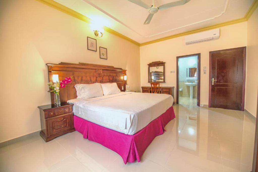 a bedroom with a large bed with a wooden headboard at Frsan Plaza Juffair in Manama