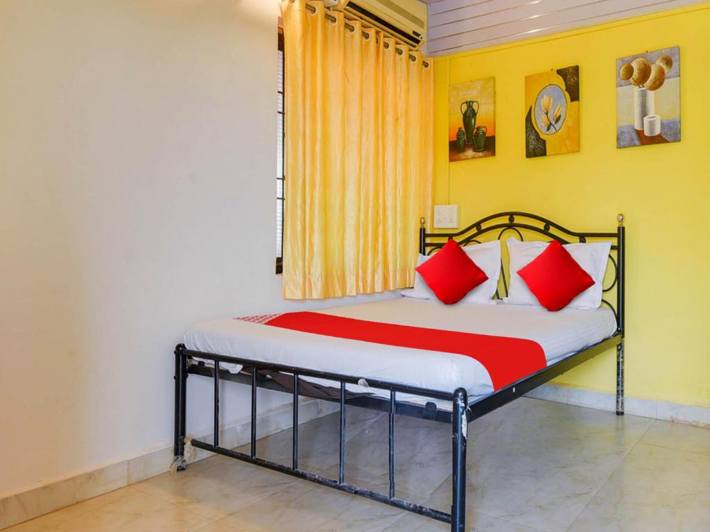 a bedroom with a bed with red pillows and a window at Hotel O Madan Motels in Goa