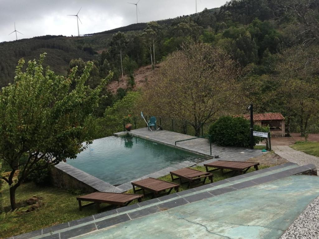 a swimming pool with picnic tables in front of a hill at Pátio do Xisto in Gondramaz