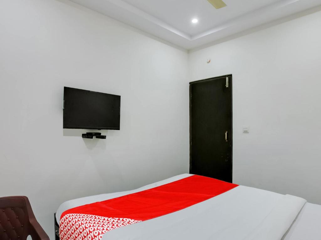 a bedroom with a bed and a flat screen tv at Hotel O Manjushree Boarding & Lodging nearby Dr.BR Ambedkar Stadium Basveshwar nagar in Bengaluru
