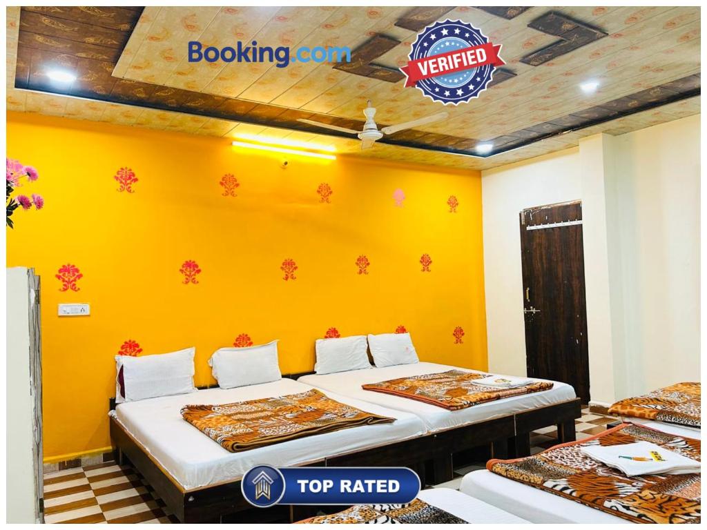 two beds in a room with a yellow wall at Hotel BNK Residency Near Temple and Railway Station in Ujjain