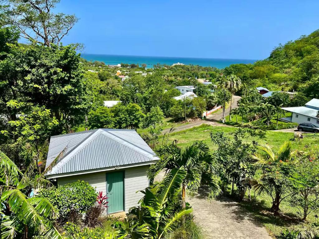 una piccola casa bianca su una collina con alberi di Bungalow vue mer - Deshaies a Deshaies