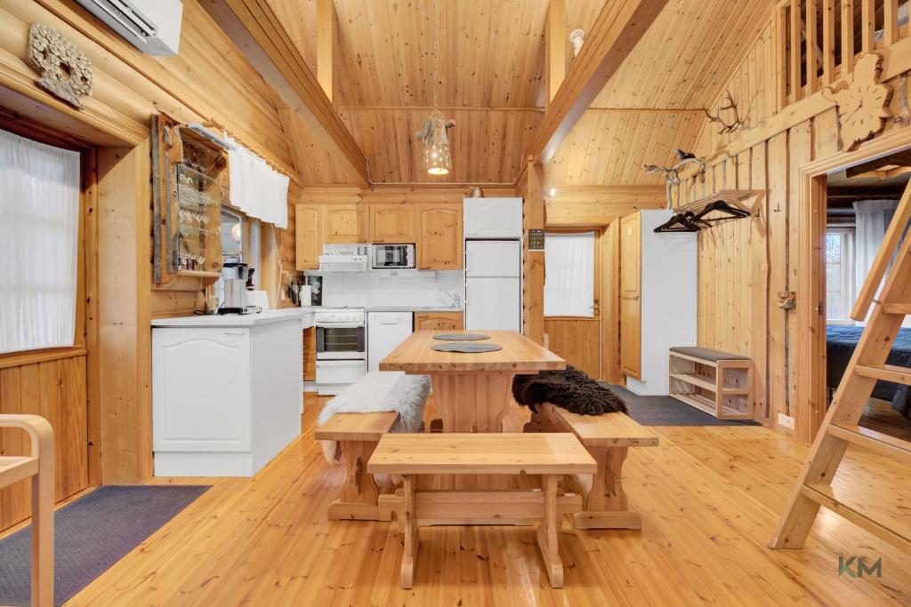 a living room with a table and a kitchen at Villa Aurora - Valkea Homes in Pelkosenniemi