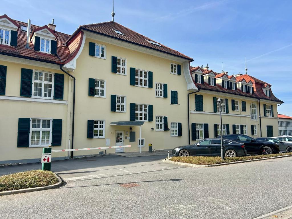 Un gran edificio con coches aparcados en un estacionamiento. en Ana Marija Apartment - Vila Golf, en Rogaška Slatina