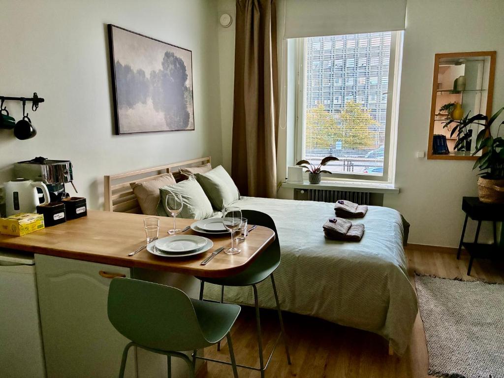 ヘルシンキにあるCozy studio in the center of Helsinkiのベッドルーム1室(ベッド1台、テーブル、グラス付)