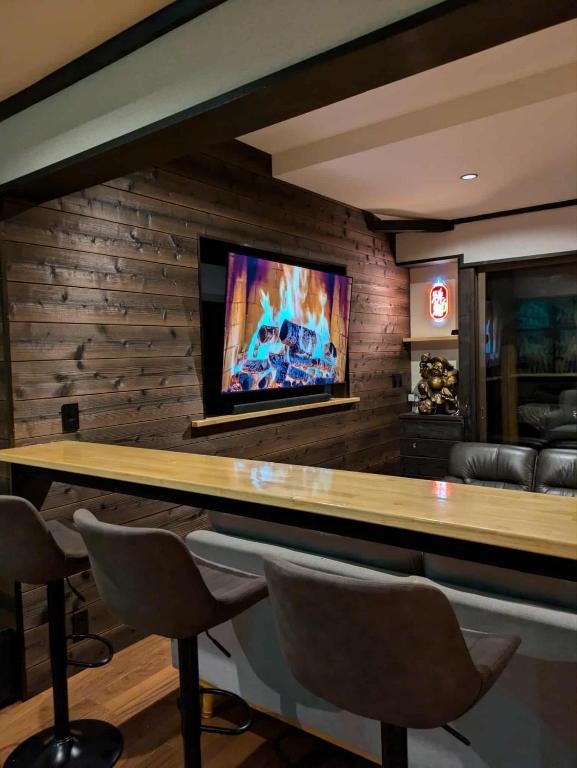a bar with chairs and a television on a wall at The Nook Hakuba in Hakuba