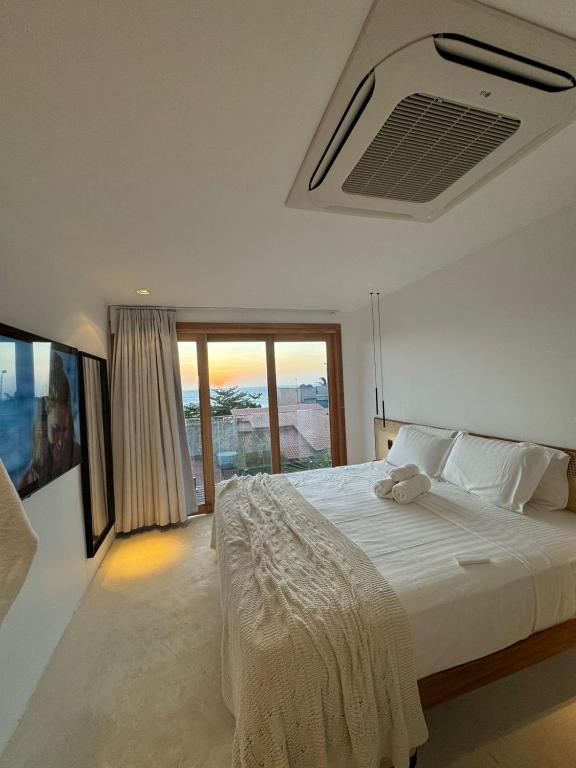 a bedroom with a large white bed with a window at Pousada Amazing Jeri in Jericoacoara