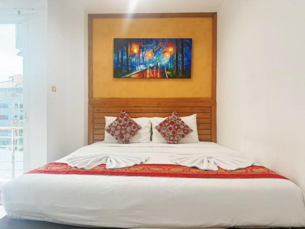 a bedroom with a bed with a painting on the wall at Abby's House Hotel in Patong Beach