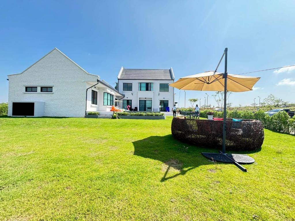 an umbrella in a yard in front of a house at Gaia Luxury Pool Villa Khao Yai in Ban Bung Toei