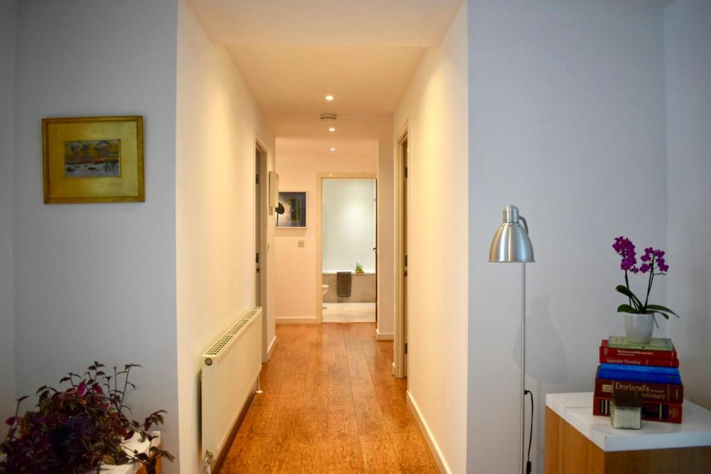 a hallway with white walls and wooden floors at Private room and bathroom in shared flat with parking in Glasgow