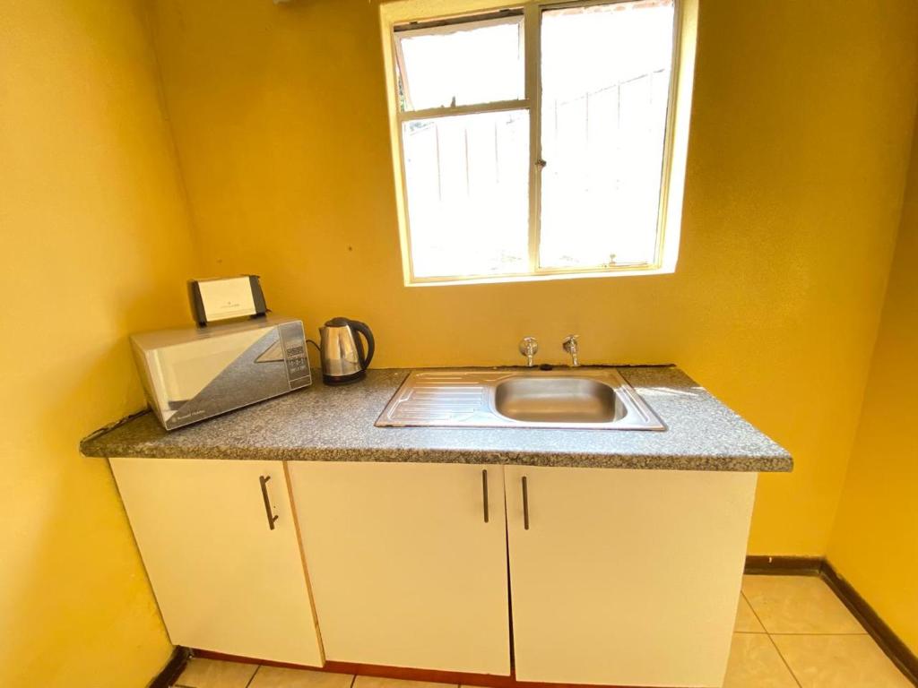 a kitchen counter with a sink and a window at Gabriel cottage in Mbabane