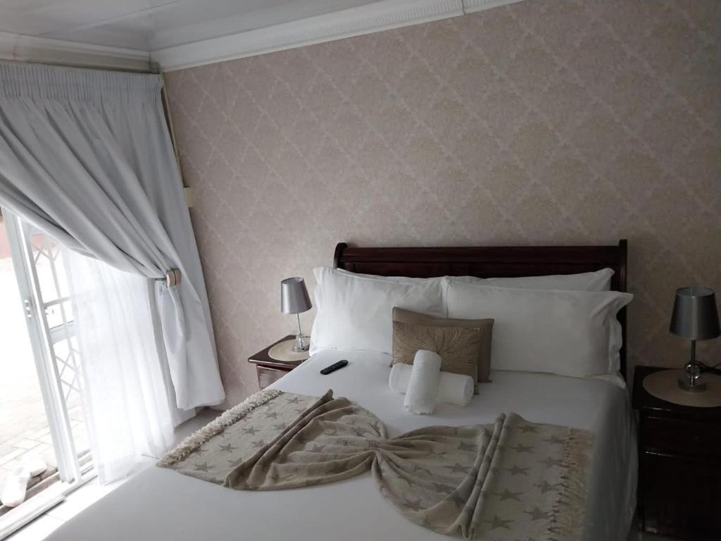 une chambre avec un lit blanc avec une fenêtre dans l'établissement Liyoli Guesthouse, à Mthatha