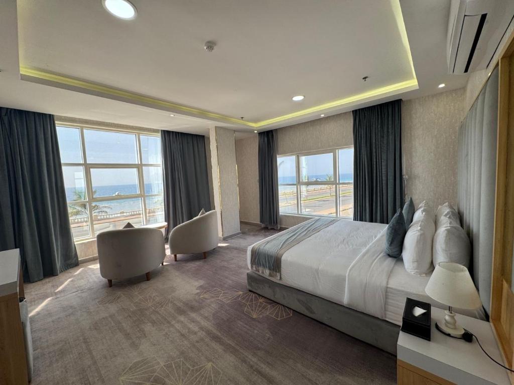 a hotel room with a bed and large windows at Rose Land Hotel in Umm Lujj