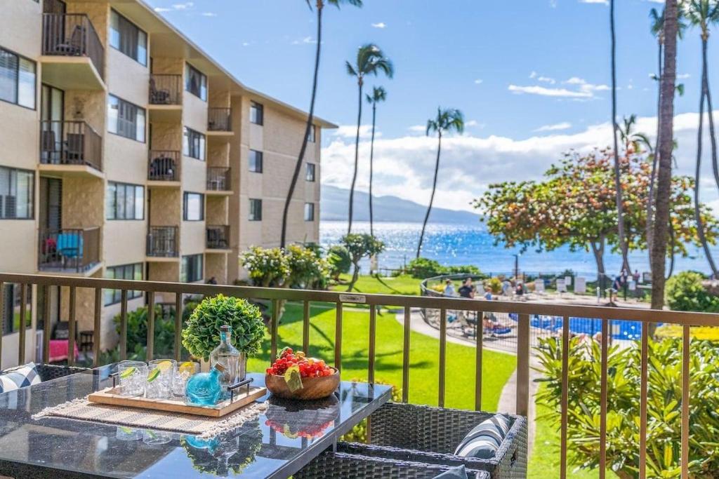 a table on a balcony with a view of the ocean at Kanai A Nalu 211 · KAN 211 Remodeled OceanFront 2BD for Whale Wa in Wailuku