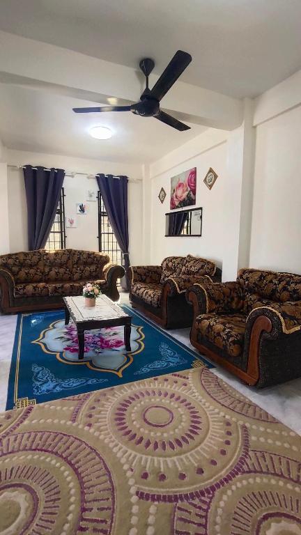 a living room with couches and a table on a rug at Fahim Homestay in Pasir Mas