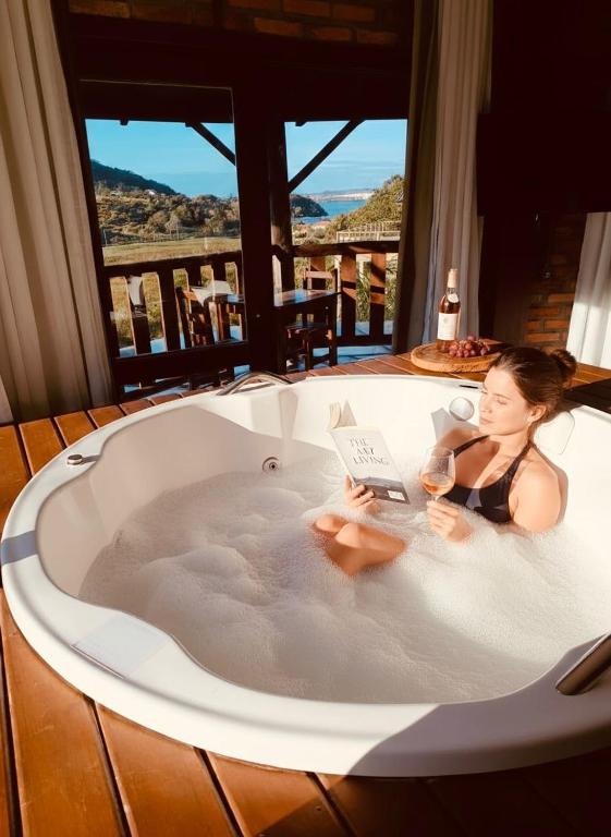 a woman sitting in a bath tub with a laptop at Pousada La Creación in Praia do Rosa