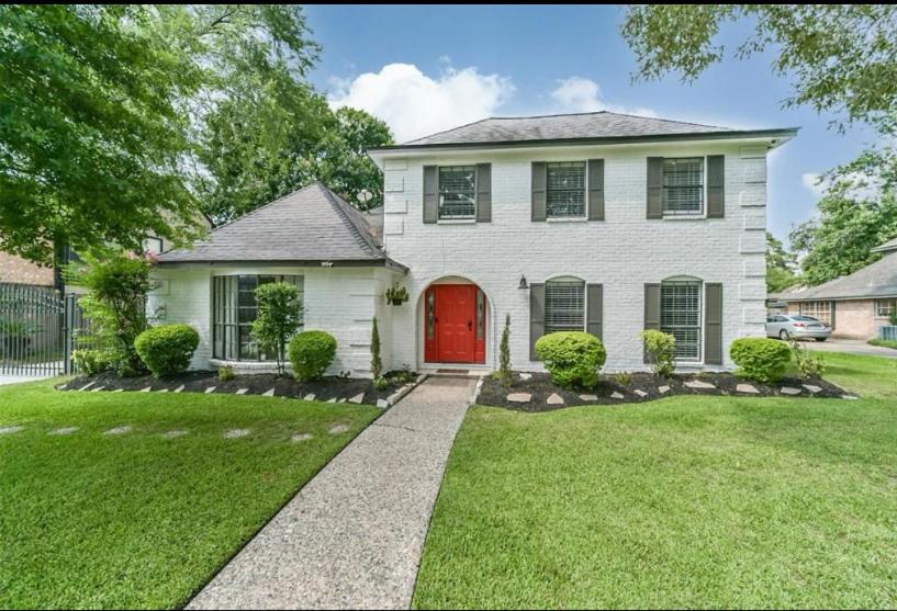 ein weißes Haus mit einer roten Tür in der Unterkunft Affordable 4 bedrooms home with a pool! in Houston