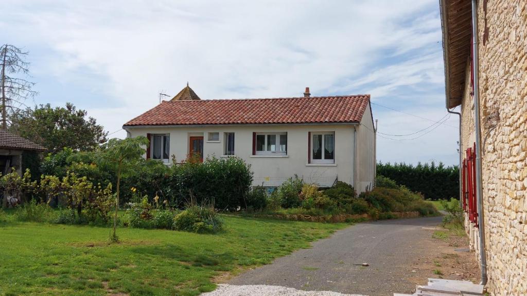 een wit huis met een rood dak op een straat bij Chez Mémé, gite proche Futuroscope in Saint-Clair