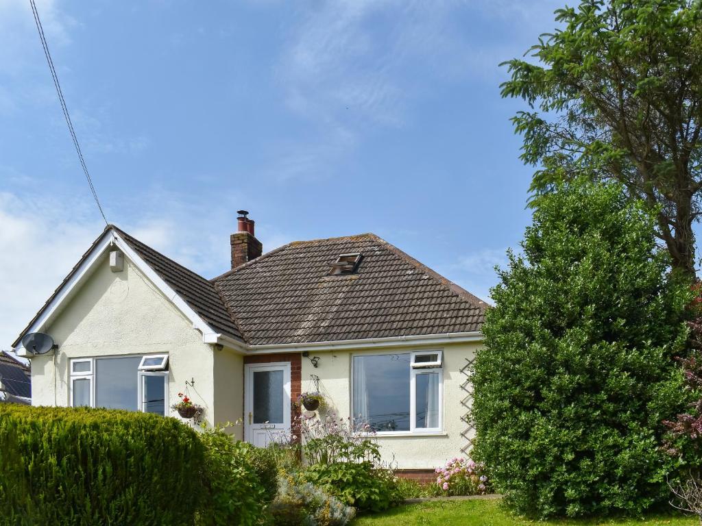 a white house with a tree in the yard at Riversong in Rhyl