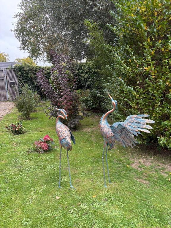 two statues of birds standing in the grass at Efes home in Ghent