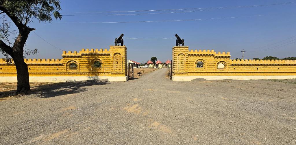 a yellow fence with statues on top of it at White Rann Resort Dholavira in Dholovira