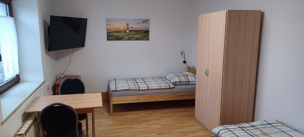 a small room with a bed and a desk and a television at Pension Hänsel in Thiendorf
