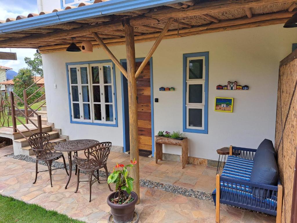 a patio with a table and chairs and a house at Chalé Antúrios - Lavras Novas in Lavras Novas