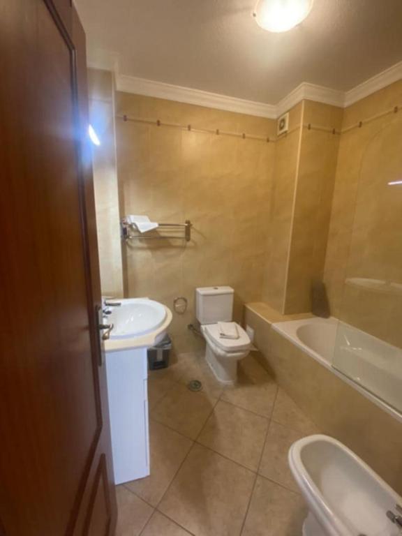 a bathroom with a toilet and a tub and a sink at Monte Fino Bech in Monte Gordo