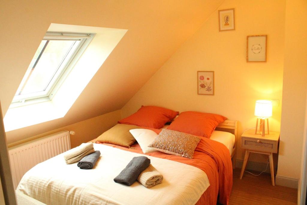 Un dormitorio con una cama con almohadas naranjas y una ventana. en Le Saint Georges, en Chinon