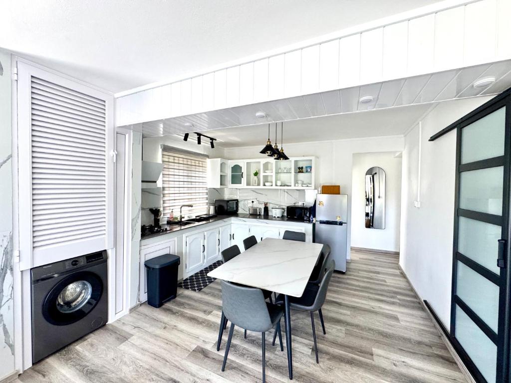 a white kitchen with a table and chairs at Le Repos Blue Apartment in Pereybere
