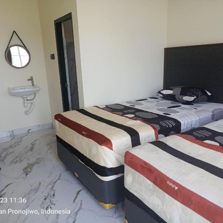 two beds sitting next to each other in a bedroom at AJA Homestay in Pronojiwo