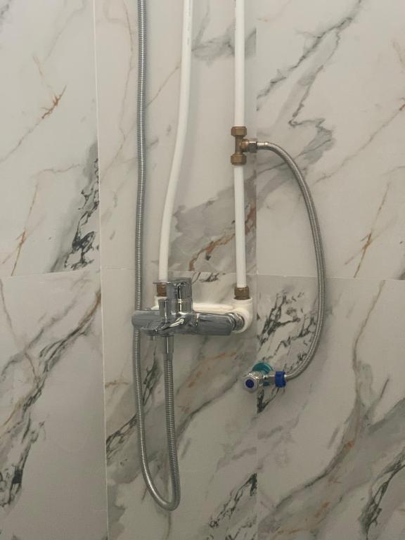 a shower in a bathroom with a marble wall at AJA Homestay in Pronojiwo